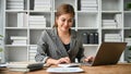 A beautiful Asian businesswoman using a calculator and working on her work on her laptop Royalty Free Stock Photo