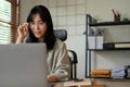 Beautiful Asian businesswoman wearing eyeglasses working on her project on laptop Royalty Free Stock Photo
