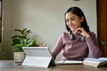 A beautiful Asian businesswoman working on her business tasks on her digital tablet at her desk Royalty Free Stock Photo
