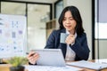 A beautiful Asian businesswoman is working at her desk in a modern office, using a tablet Royalty Free Stock Photo