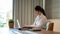A beautiful Asian businesswoman working on her laptop at a meeting table in a meeting room alone Royalty Free Stock Photo