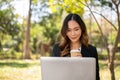 A beautiful Asian businesswoman is working remotely in a park in the afternoon Royalty Free Stock Photo