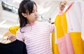 Beautiful asian child girl choosing clothes in clothing shop in shopping center,female teen customer buying new fashion long