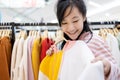 Beautiful asian child girl choosing clothes in shopping center,happy smiling woman customer buying new fashion long sleeved t- Royalty Free Stock Photo