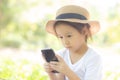 Beautiful asian child smiling using smart mobile phone in the garden, kid have passion playing game digital on smartphone