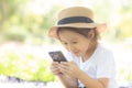 Beautiful asian child smiling using smart mobile phone in the garden, kid have passion playing game digital on smartphone
