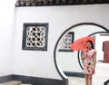 Beautiful Asian Chinese woman in traditional chi-pao cheongsam hold red parasol in a garden stand under arched door Royalty Free Stock Photo