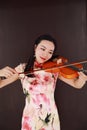 Beautiful Asian Chinese woman in traditional chi-pao cheongsam play violin in a garden pure black background Royalty Free Stock Photo