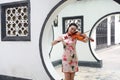 Beautiful Asian Chinese woman in traditional chi-pao cheongsam play violin in in a garden stand under arched door Royalty Free Stock Photo