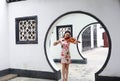 Beautiful Asian Chinese woman in traditional chi-pao cheongsam play violin in in a garden stand under arched door Royalty Free Stock Photo