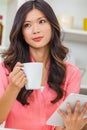 Asian Chinese Woman Using Tablet Computer Drinking Coffee or Tea Royalty Free Stock Photo