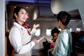 Beautiful Asian female air hostess standing at airplane entrance gate, flight attendant woman welcome and check passenger before