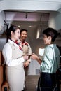 Beautiful Asian female air hostess standing at airplane entrance gate, flight attendant woman welcome and check passenger before