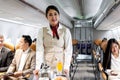 Beautiful Asian female cabin crew air hostess serving food and drink beverage to passengers on airplane, flight attendant push Royalty Free Stock Photo