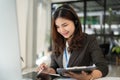 A beautiful Asian female call centre operator with a wireless headset is using her tablet Royalty Free Stock Photo