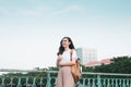 Beautiful Asian female college student holding her books stands and dresses up in street fashion cloth at outdoor public space Royalty Free Stock Photo