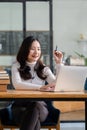 A beautiful Asian female college student studying online on a laptop computer, searching the web for information on education at a Royalty Free Stock Photo