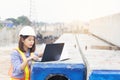 Beautiful Asian female engineer in white safety hard hat using laptop computer notebook doing job at construction site outside Royalty Free Stock Photo