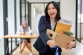 A beautiful Asian female office worker is carrying a cardboard box, feeling happy to resign Royalty Free Stock Photo