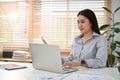 Beautiful Asian female office worker or secretary using her laptop at her desk Royalty Free Stock Photo