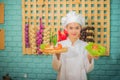 Beautiful asian female professional chef holding bowl of fresh green vegetables with smile in kitchen full of cooking ingredients. Royalty Free Stock Photo