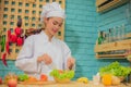 Beautiful asian female professional chef stirring bowl of fresh green vegetables with a spatula in kitchen. Royalty Free Stock Photo