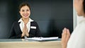 Beautiful Asian female receptionist greeting and welcoming a customer at the front desk