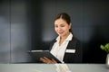 A beautiful Asian female receptionist reading and checking a document at front desk Royalty Free Stock Photo