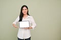 Beautiful Asian female showing tablet mockup, standing against grey studio background Royalty Free Stock Photo