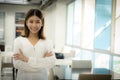 The beautiful asian female teacher is standing with arms crossed and looking at the camera with a smiling face in the classroom Royalty Free Stock Photo