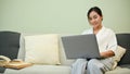 Beautiful Asian female using laptop computer on her comfy sofa in her living room Royalty Free Stock Photo