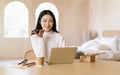 Beautiful Asian Freelancer woman holding phone speak activate virtual digital voice assistant or loudspeaker talking on smartphone Royalty Free Stock Photo