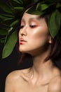 Beautiful Asian girl with a bright make-up art in green leaves. Beauty face. Creative image.