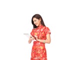 Beautiful Asian girl in Chinese qipao traditional dress using digital tablet, Chinese new year and modern technology concept