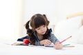 Beautiful Asian girl drawing and doing homework on the bed. Children relax and free time for creative her play.