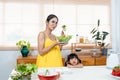 beautiful Asian girl and her lovely daughter are cooking in kitchen, The daughter sitting was eating sausage on her lap, both her Royalty Free Stock Photo