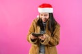 Beautiful Asian girl in a long-sleeved shirt and a Christmas hat. holding a tablet in hand and expressing joy
