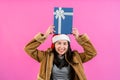 Beautiful Asian girl in a long-sleeved shirt and Christmas hat. lifted blue gift box and placed on head, rejoicing because had Royalty Free Stock Photo