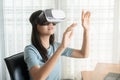 Beautiful Asian girl are looking through vr glasses to play games at home, woman is using glasses with virtual reality headsets at