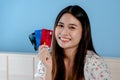 A beautiful Asian girl, is ordering online through a laptop computer, holding three credit cards in her hand, in order to choose Royalty Free Stock Photo