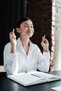 Beautiful asian girl sitting at a table for an interview and crossing her fingers in the hope of closing her eyes Royalty Free Stock Photo