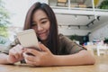 A beautiful Asian girl with smiley face holding and using smart phone Royalty Free Stock Photo