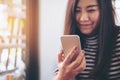 A beautiful Asian girl with smiley face holding and using smart phone Royalty Free Stock Photo