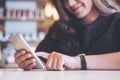 A beautiful Asian girl with smiley face using , pointing and looking at smart phone Royalty Free Stock Photo