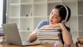 A beautiful Asian girl student is listening to music, napping on stack of books, falling asleep Royalty Free Stock Photo