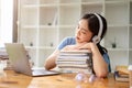 A beautiful Asian girl student is listening to music, napping on stack of books, falling asleep Royalty Free Stock Photo