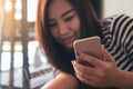 A beautiful Asian girl using smart phone with smiley face and feeling relax Royalty Free Stock Photo