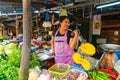 Beautiful Asian girl vegetable seller at the market lifts a dumbbell to keep fit