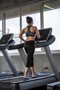 Beautiful asian girl is walking on a treadmill in the gym.She Send your eyes with pleasure in exercise because it makes her Royalty Free Stock Photo