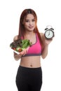 Beautiful Asian healthy girl with clock and salad.